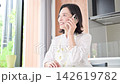 A video showing a woman, possibly a housewife in her 50s, smiling and talking on her smartphone at home, chatting with family and friends in between household chores. 142619782