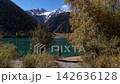 Hiker admiring serene turquoise mountain Issyk's lake view, Kazakhstan 142636128