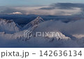 Aerial view of snowy mountain peaks above clouds, Norway 142636134