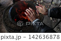 Warm hands gather around flickering flames in a chilly outdoor setting 142636878