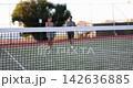 Enjoying a playful tennis match at sunset with friends by the scenic court 142636885