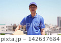 A delivery person walks with a serious expression under a blue sky. 142637684