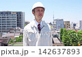A male site supervisor walks with a serious expression under a blue sky. 142637893