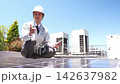 Technicians performing maintenance on solar panels on a rooftop 142637982
