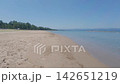 A vast sandy beach and a seascape under a clear blue sky. 142651219