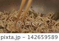 Eating hot noodle soup from a metal bowl close-up 142659589