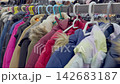 A variety of winter jackets in different colors and styles hang on display in a clothing store aisle, showcasing the range of options available for customers looking for used clothing 142683187