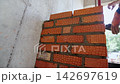 Builder hand removes excessive concrete mix from brickwork 142697619