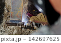 Laborer in gloves welds metal carcass at construction site 142697625
