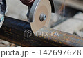 Worker cuts hollow structural section with circular saw 142697628