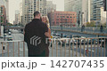 A loving couple kissing against the backdrop of big city buildings. A romantic moment at sunset. Urban setting. 142707435