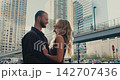 A creative romantic shot of a loving couple in a big city at sunset. A woman and a man dressed in the same style hug each other and smile gently. 142707436