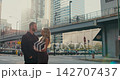 A creative romantic shot of a loving couple in a big city at sunset. A woman and a man dressed in the same style hug each other and smile gently. 142707437