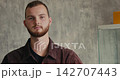 Bearded male model adjusting jacket against minimalistic backdrop with soft lighting 142707443