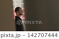 Creative profile shot of a young man seen through a door gap, standing in a room, thoughtful and deeply focused. 142707444