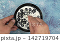 Person mixing blueberries and yogurt in a black bowl 142719704