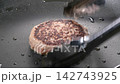 黒い鉄板で焼き目をつけて焼くハンバーグ 142743925
