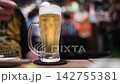 A man picks up a beer mug placed on the table and drinks it all. 142755381