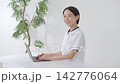 Woman in a white coat, using a computer. 142776064