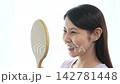 A woman with eyelash extensions looks in the mirror. 142781448