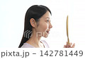 A woman with eyelash extensions looks in the mirror. 142781449