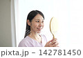 A woman with eyelash extensions looks in the mirror. 142781450