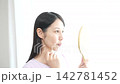A woman with eyelash extensions looks in the mirror. 142781452