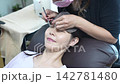 Woman receiving eyelash extension treatment 142781480