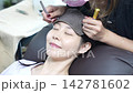 A woman with eyelash extensions looks in the mirror. 142781602
