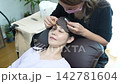 A woman with eyelash extensions looks in the mirror. 142781604