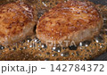 黒いフライパンでソースがかかった2個のハンバーグが煮詰まる様子の動画 142784372