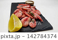Pink shrimps with lemon slices and spices lie on a black slate board on a white background, the camera moves smoothly to the side. The concept of seafood, cooking, seasoning. High quality 4k footage 142784374