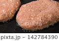 黒い鉄板で焼き目をつけて焼くハンバーグ 142784390
