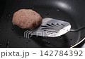 黒い鉄板で焼き目をつけて焼くハンバーグ 142784392