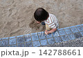 公園の砂場でしゃがんで手で砂遊びをする子供 142788661