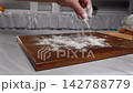 Sprinkling Flour on a Wooden Surface for Baking: Preparation for Delicious Homemade Recipes 142788779