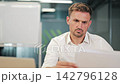 Professional Man Reviews Business Documents In Modern Office 142796128