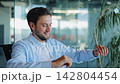 Businessman in Light Blue Shirt Relaxing and Stretching in Modern Office 142804454