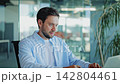Corporate Analyst Concentrates on Laptop and Takes Notes in Modern Office 142804461