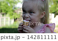 Portrait of cute blonde girl eating delicious ice cream in a waffle cone outdoor. Beautiful small child enjoying a sweet cold dessert in a summer garden. Innocent little kid tasting refreshing food 142811111