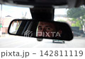 Eyes of male smiling driver reflecting in rearview mirror while riding motor auto. Young man looking concentrated to urban road during operating vehicle. Confident guy driving modern car at city 142811119
