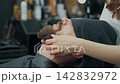 Barber Applying Lotion to Clients Beard 142832972