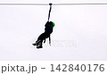Child enjoys riding on zip-line with grey clouds in backdrop 142840176