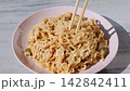 Creamy noodle dish served in a pastel pink ceramic plate 142842411