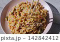 Creamy noodle dish served in a pastel pink ceramic plate 142842412