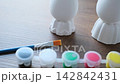 Close-up of hands painting colorful Easter eggs with a paintbrush 142842431