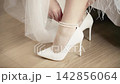 Wedding day details with bride adjusting her high-heeled shoes before ceremony 142856064