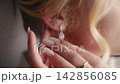 Wedding day moments with a bride adjusting her earrings before the ceremony 142856085