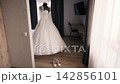 Wedding dress displayed in a room with shoes ready for the wedding ceremony 142856101