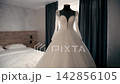Wedding dress displayed in a room on the special day with soft light enhancing the fabric and design in the background 142856105